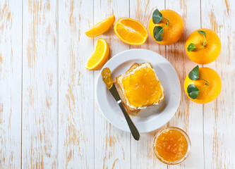 Delicious toasts with orange marmalade or orange jam on kithen table, top view.