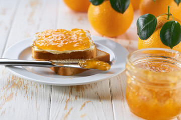 Delicious toast with orange jam on the wooden kitchen table.
