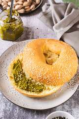 Bagel with pistachio cream butter and a jar of butter on a plate on the table vertical view
