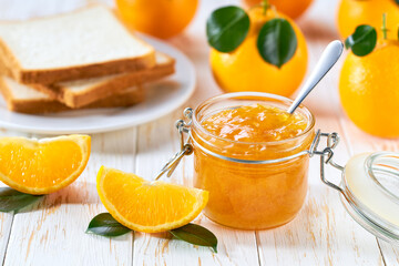 Plate with slices of bread and delicious orange jam on wooden table. Bread and orange homemade jam on wooden table.