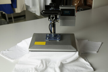 Printing logo. Heat press with t-shirt on white table
