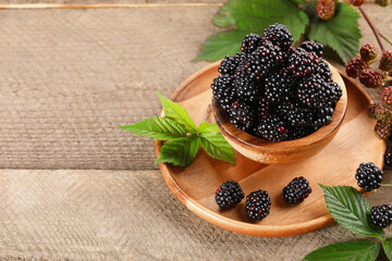 Fresh ripe blackberries and leaves on wooden table. Space for text