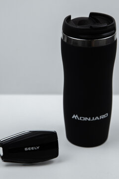  The key from the car to the thermocup of black color on which it is written GEELY MONJARO, stand on a white background. High quality photo