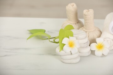 Composition with different spa products and plumeria flowers on white marble table, space for text