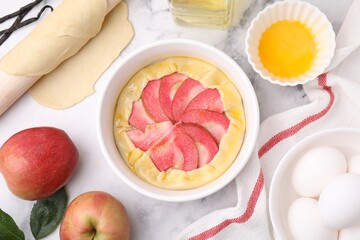 Flat lay composition with fresh dough, apples and other ingredients on white marble table. Making galette