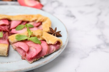 Delicious apple galette with mint and anise on white marble table, closeup. Space for text