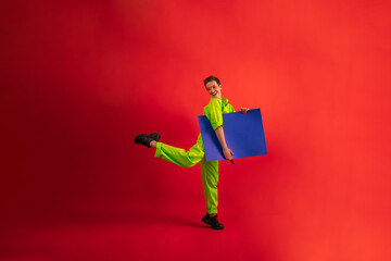 middle age woman with short haircut wear green overalls posing with cardboard on red background....