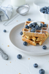 Belgian waffles with blueberries and honey on a white background. Serving breakfast with homemade cakes.