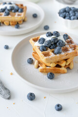 Belgian waffles with blueberries and honey on a white background. Serving breakfast with homemade cakes.