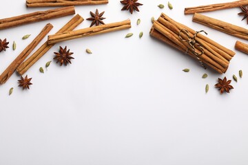 Cinnamon sticks, star anise and cardamom pods on white background, flat lay. Space for text