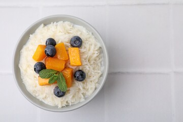 Bowl of delicious rice porridge with blueberries and pumpkin on white table, top view. Space for text