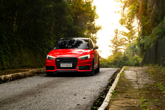Cinematic shot of an Red Audi A1 on empty road against sunset light, nature surroundings - High Resolution Images