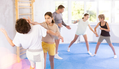 Obraz premium Children in sparring improve skill of performing strangulation and neutralizing enemy during krav maga class. Pupils strike out at mandible and body at self-defense lesson