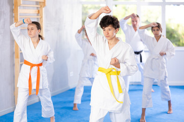 In gym, certified master coach conducts karate kata lesson with children boys girls team students...