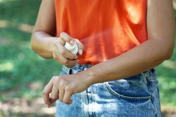 Girl spraying insect repellent on her arm outdoor in nature using spray bottle. Mosquito repellent....