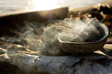 An image of a burning smudge kit with golden sunlight in the background. 