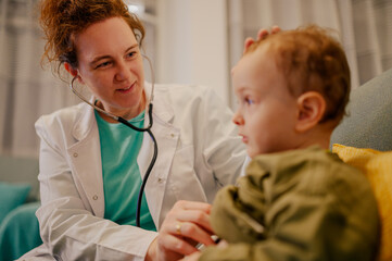 A friendly pediatrician is visiting her patient at home and examining him.