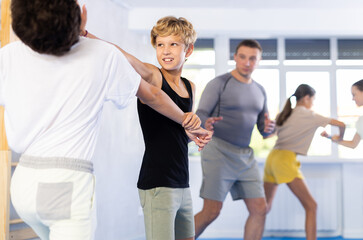 Two preteen boys learn to do power grabs in pairs during a self-defense lesson under the guidance...