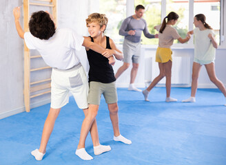 Two boys practicing self-defense techniques in group at gym