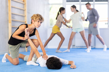 Fototapeta na wymiar Children boy and girl partner in sparring practice technique practicing basic attacking movements and maneuvers. Class self-defense training in presence of experienced instructor. Wrestling as an art