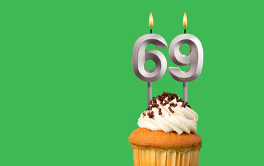 Birthday with number 69 candle and cupcake - Anniversary card on green color background