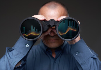 Businessman with binoculars looking at stock exchange