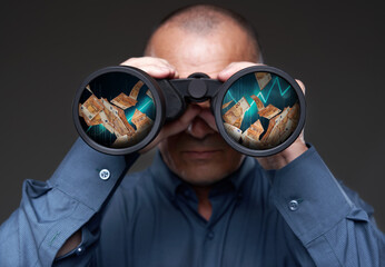 Businessman with binoculars looking at cash flying