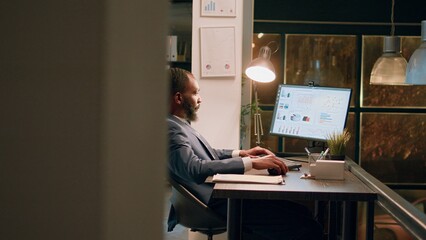 Business administrator showing assistant project results on laptop, crosschecking financial information during nightshift. Company staff personnel working in modern office overnight