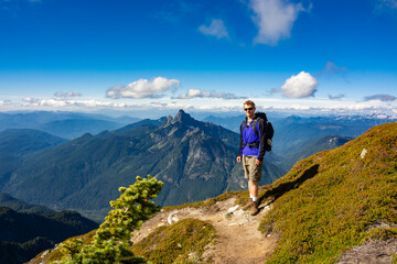 Adventurous athletic male hiker standing on a hiking trail on top of a rugged mountain at at the...