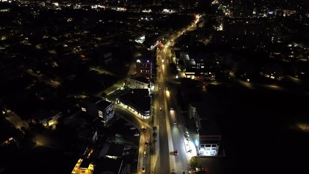 Aerial view of the cityscape of Limassol at night. Streets of the evening city with the light of car headlights on the roads and houses with windows. High quality 4k footage
