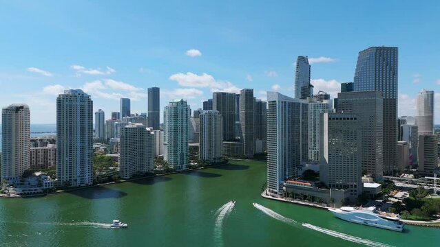 Amazing drone view of modern skyscrapers and buildings located near coastline of ocean on sunny day. Sailboats in water moving along Brickell in Miami, Florida
