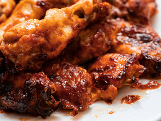 Close up of cooked chicken wings on a plate. Popular poultry product. Greasy food.