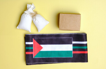 A picture of Palestine flag with box and bag of flour miniature. Humanitarian aid to Palestine