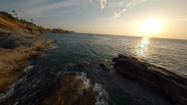 Fpv drone flight around a nice yacht at a creek at Phuket island, Thailand. Aerial dynamic fast flight during beautiful sunset with small sea waves ripples