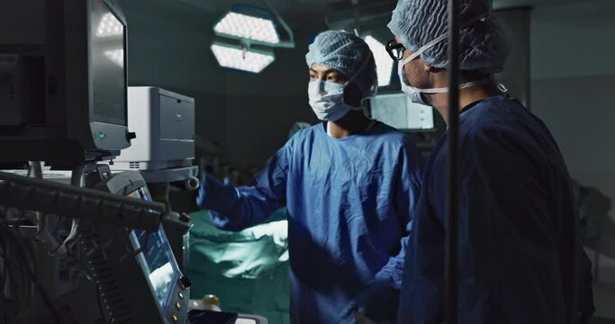 Planning, talking and surgeons in a room for surgery, teamwork and discussion about healthcare. Dark, theater and men or doctors speaking about schedule for a procedure on a screen for operation