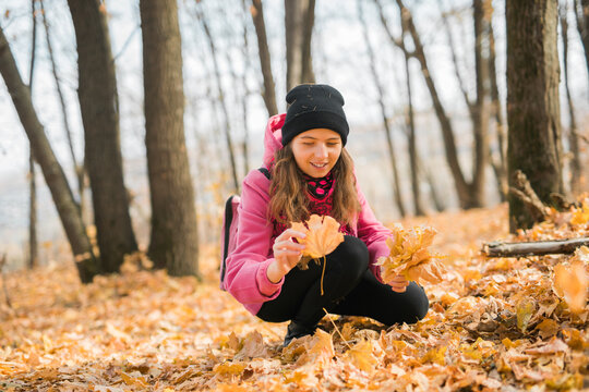 Young woman in a hat collects autumn leaves. Fall season concept. Generation Z and gen z youth