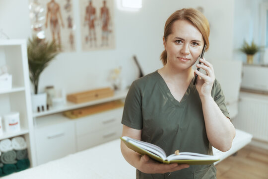 female massage therapist in massage cabinet talking on phone