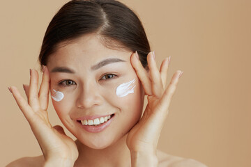 Portrait of young asian female with facial cream on face
