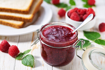 Plate with slices of bread and delicious raspberry jam on wooden table. Bread and raspberry homemade jam on wooden table