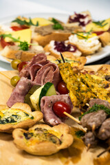 light snacks on a skewer, salami, cherry tomatoes, chicken strips, and savory tarts