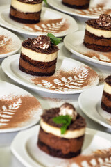 chocolate and cappuccino mini cakes on small white plates cocoa leaves garnish