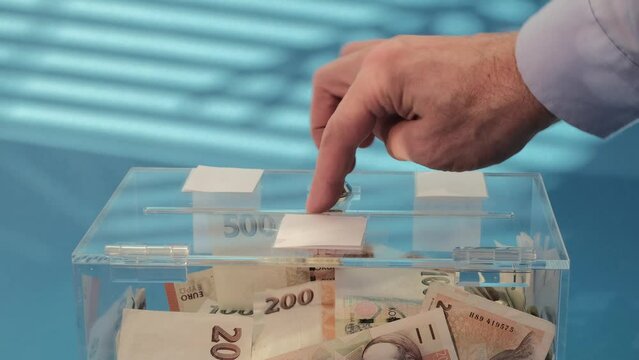 Hand put Charity and money CZK czech koruna banknotes into a transparent donation box for money donation. A financial support, collects money for a noble cause. The act of giving supports 