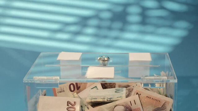 Hand pute Charity and money CZK czech koruna banknotes to a transparent donation box for money donation. A financial support, collects money for a noble cause. The act of giving supports 