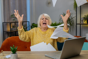 Stressed senior woman at home room looking at unpaid bank debt bills, doing paperwork, planning...