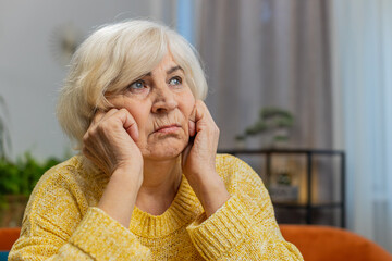 Portrait of sad stressed senior grandmother woman sitting at home looks pensive thinks over life...