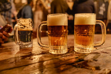 Mugs with pilsner beer in a wood table in a pub.
