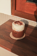 Iced Mocha Coffee with foam milk and Chocolate under morning sunlight on a wooden table with copy space. 