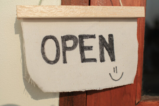 Open sign board on wooden door under morning sunlight in modern cafe coffee shop ready to service. Vintage color tone style.