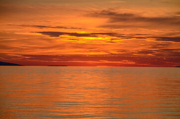 Obraz premium Beautiful orange sky and clouds above the sea after sunset. Peaceful waves on the sea in the evening.
