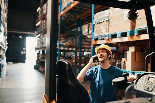 Young man talking on phone call in large warehouse